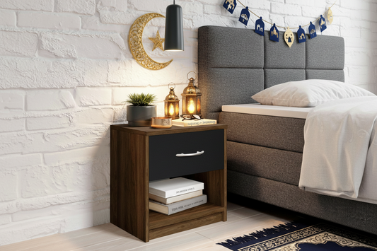 Wooden nightstand with a drawer next to a bed with a gray headboard.
